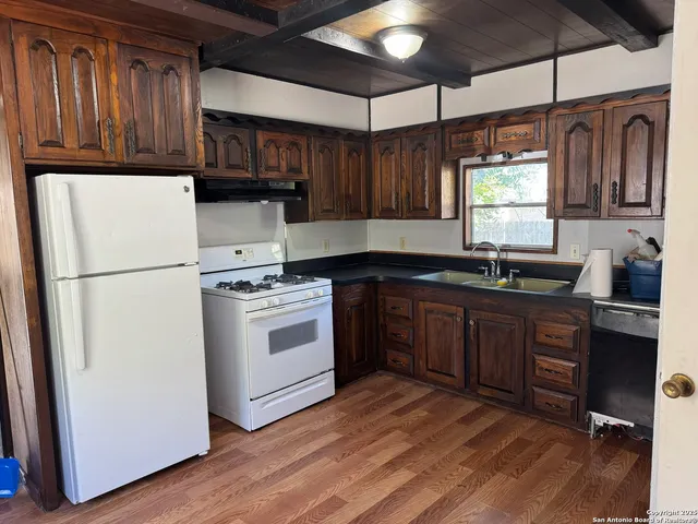 a kitchen with a refrigerator stove and sink with wooden floor