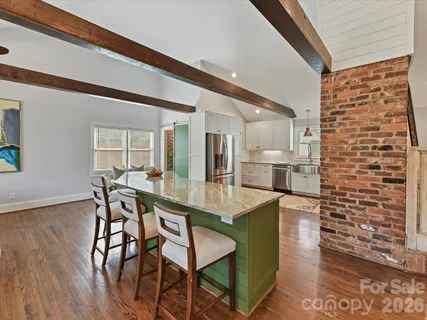 a dining hall with stainless steel appliances kitchen island granite countertop a table chairs and a refrigerator
