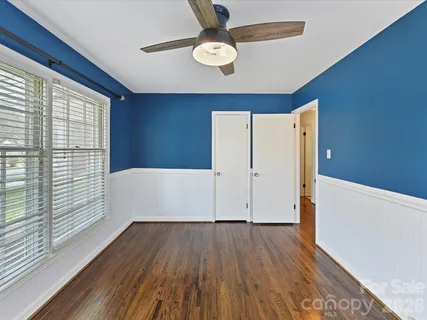 a view of empty room with wooden floor and fan