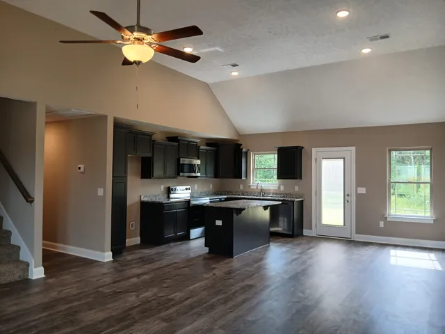 a kitchen with stainless steel appliances granite countertop a sink dishwasher stove and microwave with wooden floor