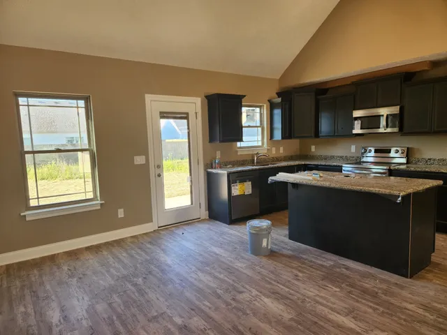 a kitchen with granite countertop a sink cabinets and wooden floor