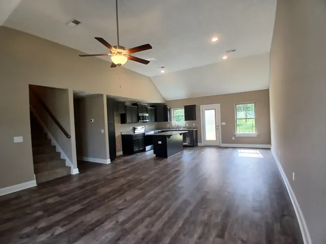 a view of an empty room with a window and kitchen view