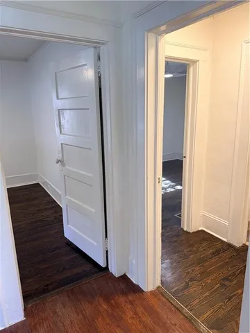 a view of an empty room with wooden floor and closet