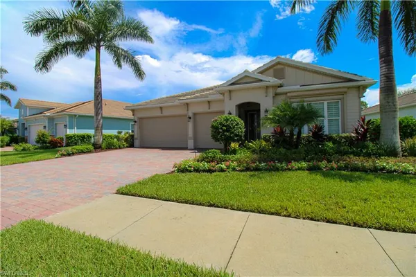 a front view of a house with a garden and palm trees