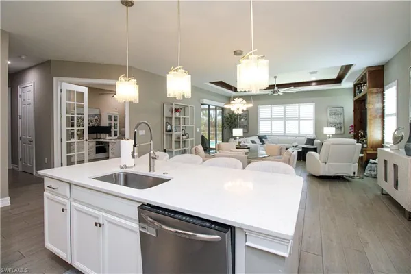 a kitchen with sink stove and white cabinets with wooden floor