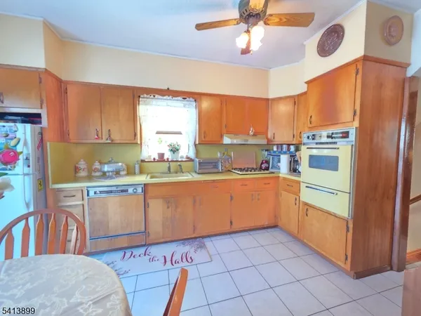 a kitchen with stainless steel appliances granite countertop a refrigerator a sink dishwasher and white cabinets with wooden floor