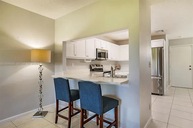 a kitchen with stainless steel appliances a dining table chairs and a refrigerator