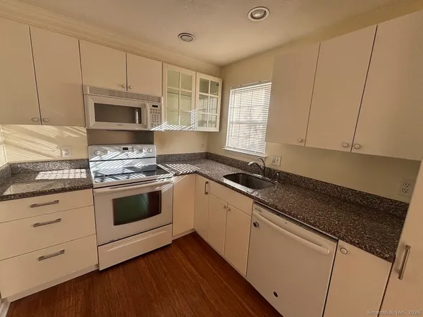a white kitchen with granite countertop stainless steel appliances