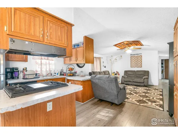 a kitchen with stainless steel appliances granite countertop a sink a stove a dining table and chairs with wooden floor