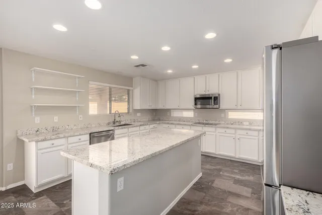 a large kitchen with granite countertop a sink and white cabinets