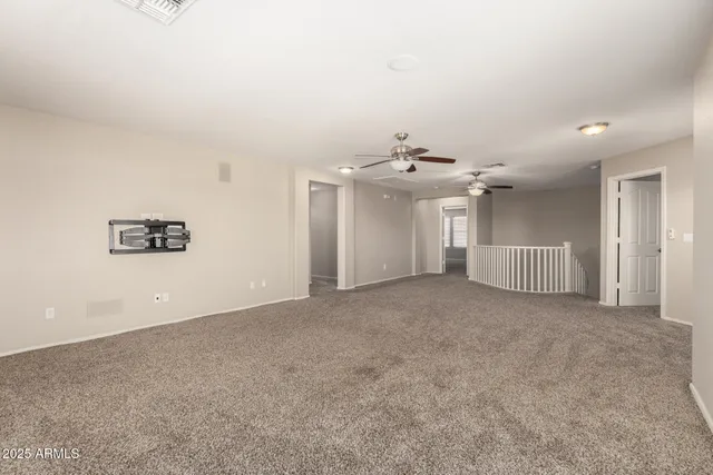 an empty room with a chandelier fan and windows