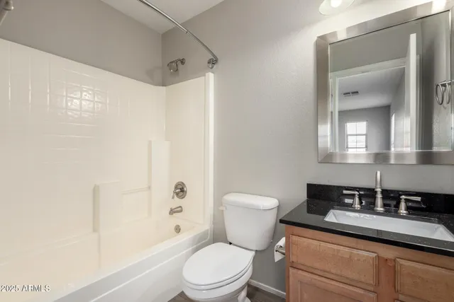 a bathroom with a granite countertop sink a toilet a mirror a bathtub and shower