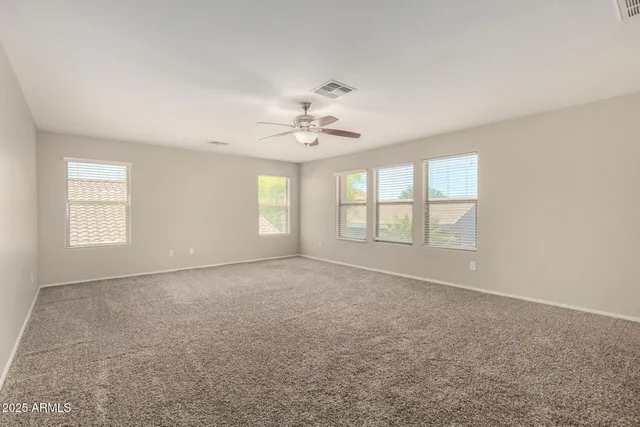 an empty room with windows and ceiling fan