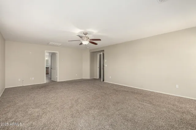 a view of an empty room with a chandelier fan