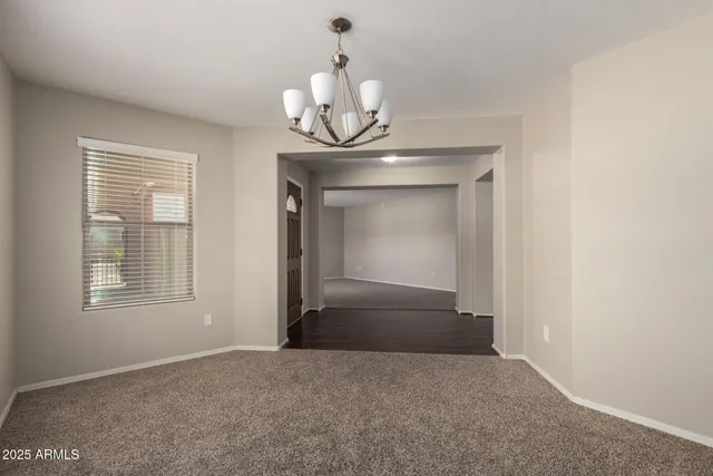 a view of an empty room with a chandelier fan and a window