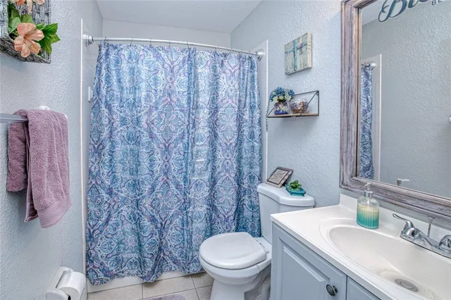 a bathroom with a granite countertop sink a toilet and a shower curtain