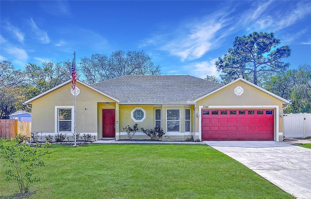7164 Toledo Road Spring Hill, FL 34606 - Photo 1 of 1 a front view of a house with a garden and yard