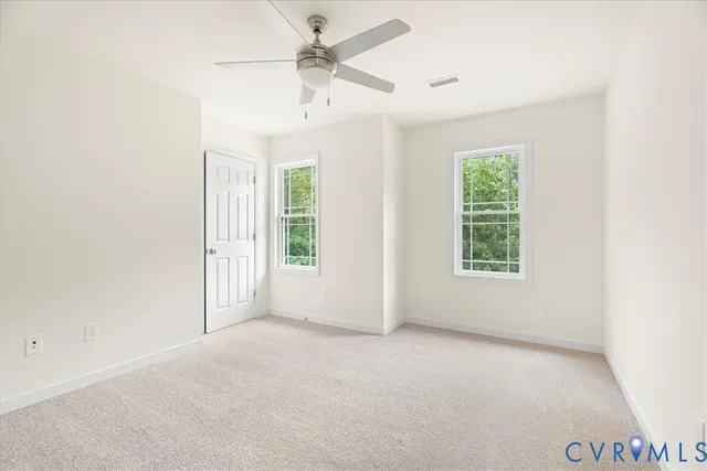 an empty room with windows and fan