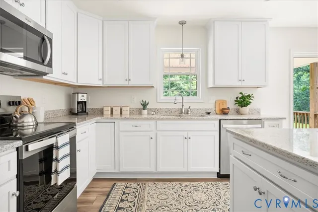 a kitchen with stainless steel appliances granite countertop white cabinets a stove a sink and dishwasher