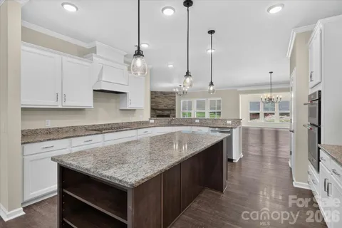 a kitchen with granite countertop white cabinets and a stove