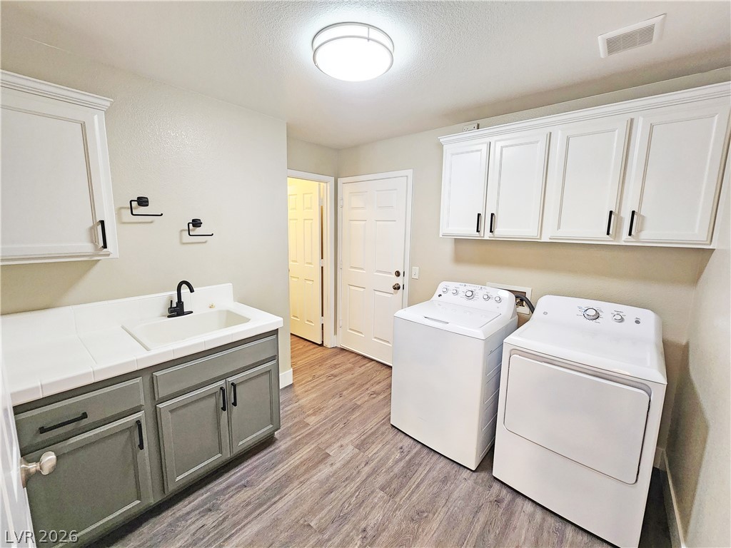 4591 Stoneham Street Pahrump, NV 89061 - Photo 19 of 42 Functional laundry space featuring a sink, practical cabinets, and modern appliances.