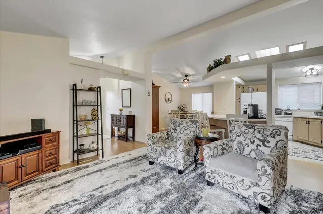 a living room with furniture a wooden floor and kitchen view