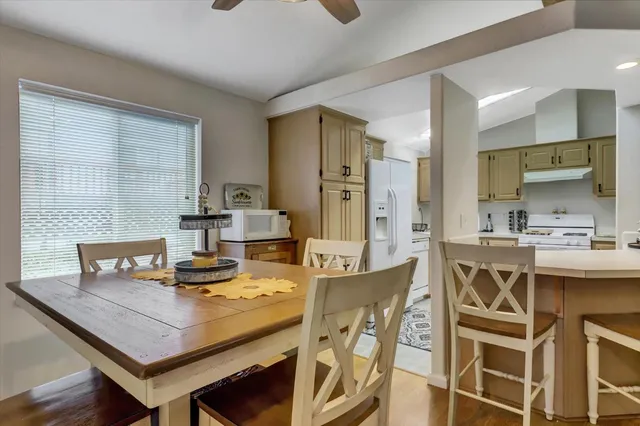 a kitchen with a stove a sink dishwasher a dining table and chairs with wooden floor