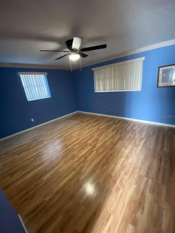 a view of an empty room with window and chandelier fan