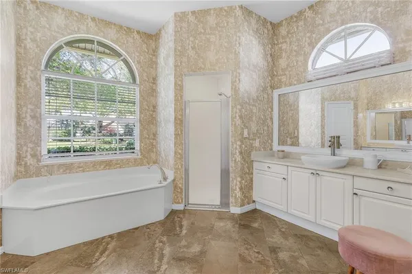 a bathroom with a sink a large mirror and a bathtub next to a window