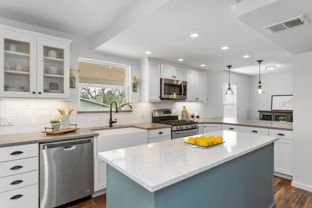 a kitchen with a sink a stove cabinets counter top space and appliances