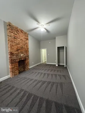 an empty room with wooden floor fireplace and windows