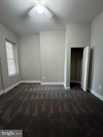 a view of an empty room with window and closet area