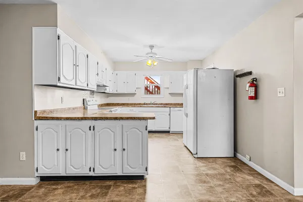 a kitchen with granite countertop white cabinets and refrigerator