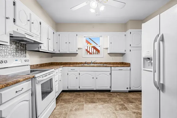 a kitchen with granite countertop white cabinets and refrigerator