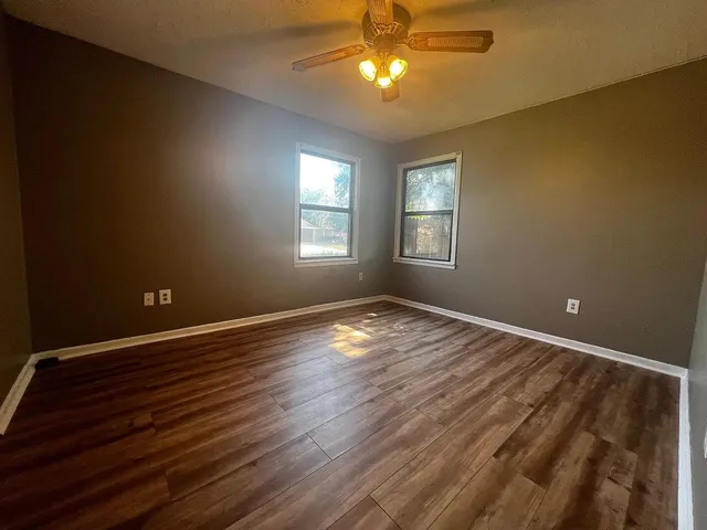 a view of empty room with wooden floor and fan