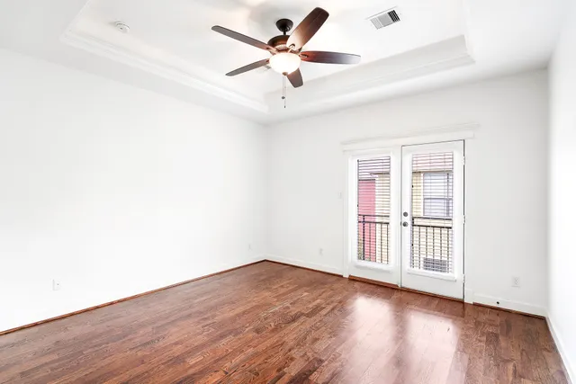 an empty room with wooden floor and ceiling fan