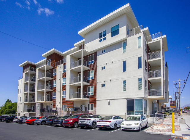 2101 North Main Street, Unit 306 Sunset, UT 84015 - Photo 21 of 22 Modern multi-story building featuring a stucco exterior, wood panel accents, multiple private balconies with metal railings, and a ground-level parking area