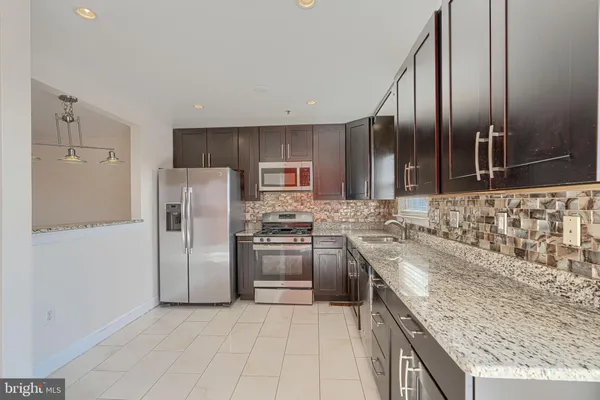 a kitchen with stainless steel appliances granite countertop a stove a sink and a refrigerator