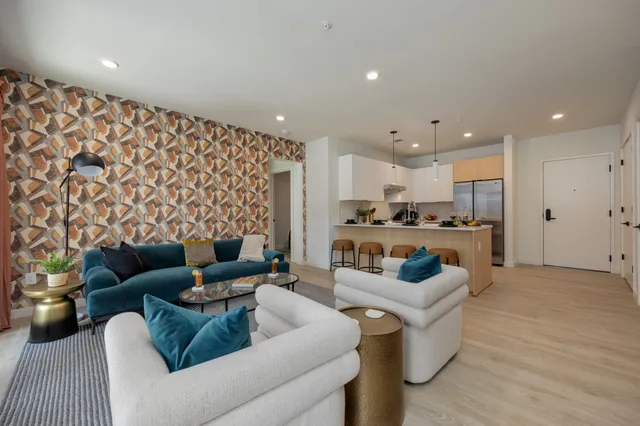 a living room with furniture and a view of kitchen