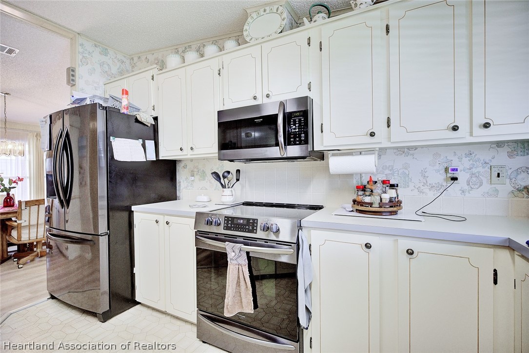 1571 Caribbean Road Sebring, FL 33870 - Photo 11 of 41 a kitchen with stainless steel appliances granite countertop a stove a refrigerator and a white cabinets