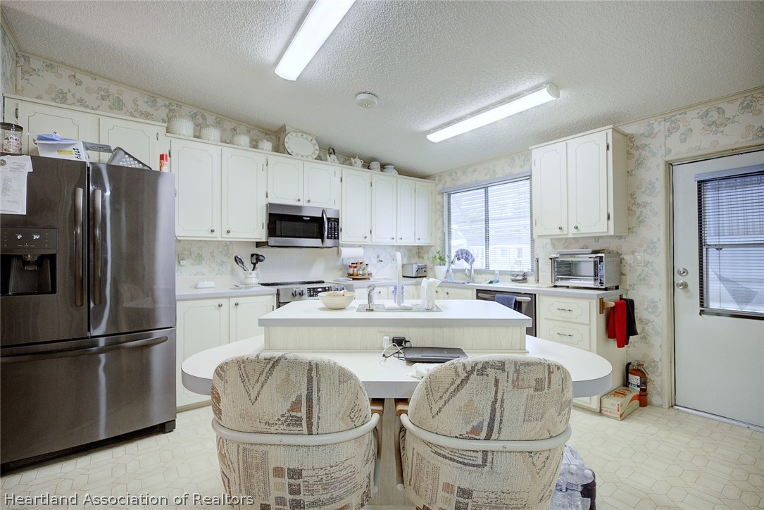 1571 Caribbean Road Sebring, FL 33870 - Photo 13 of 41 a kitchen with a refrigerator and a stove top oven