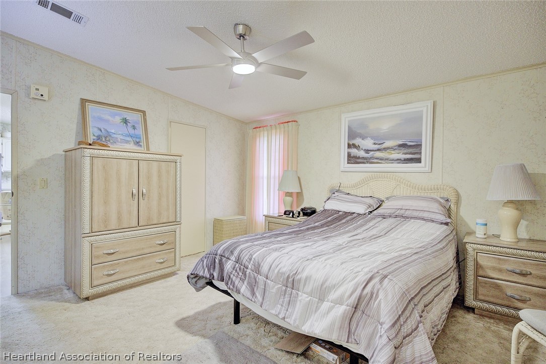 1571 Caribbean Road Sebring, FL 33870 - Photo 18 of 41 a spacious bedroom with a bed and a chandelier