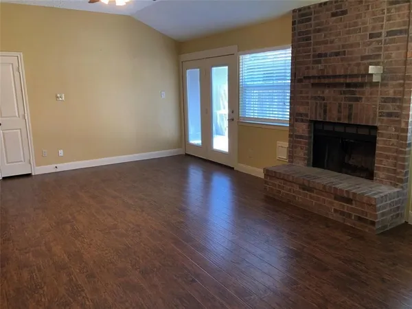 an empty room with wooden floor and fireplace