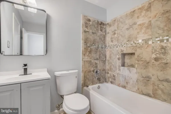 a bathroom with a toilet a sink a mirror a bathtub and vanity