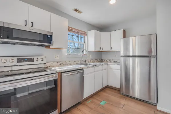a kitchen with stainless steel appliances granite countertop a refrigerator sink and white cabinets