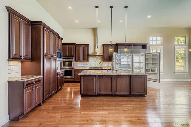 a kitchen with stainless steel appliances granite countertop wooden cabinets a stove a sink and dishwasher a refrigerator with wooden floor