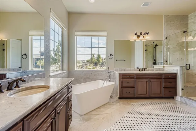 a bathroom with a granite countertop double vanity sink a mirror a bathtub and window