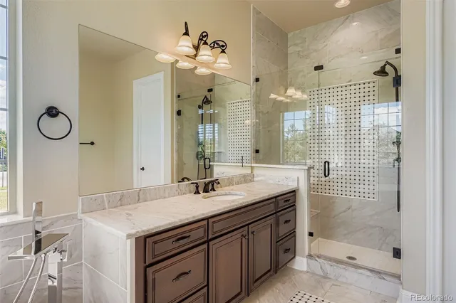 a bathroom with a granite countertop sink a mirror and a shower