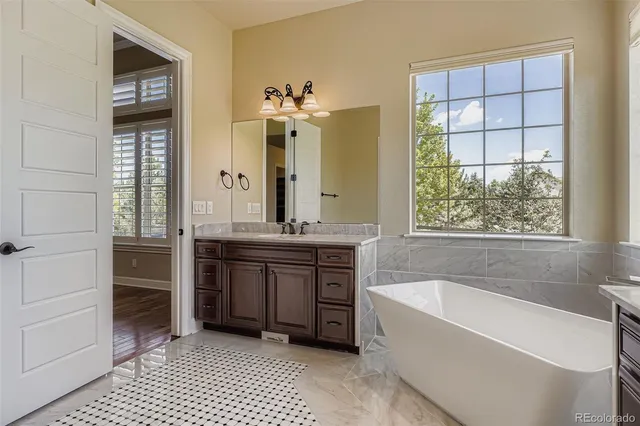 a bathroom with a tub a double vanity sink and a large mirror