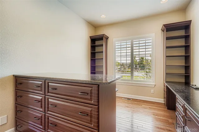 an empty room with wooden floor closet and windows